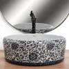 A decorative ceramic basin with a floral pattern, a black faucet, and a reflection in a mirror. Anteprima dell’immagine prodotto
