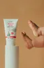 A baby's feet are shown next to a tube of sunscreen lotion placed on a white pedestal. Anteprima dell’immagine prodotto