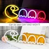 A collage showing a neon sign of Pac-Man and ghosts in two different lighting conditions, with text overlay. Voir les images du produit