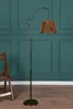 A floor lamp and a wooden chair are placed against a teal paneled wall. Produktbild-Vorschau
