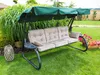 A garden swing with cushions is set up on a green lawn, surrounded by plants and flowers. Náhled obrázku produktu