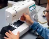 A person is using a Brother sewing machine to sew dark fabric. Produktbild-Vorschau