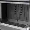 A close-up view of the interior of a fireplace insert, showing the grate and the back wall with ventilation holes. Anteprima dell’immagine prodotto