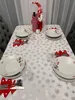 A table set for a Christmas meal with snowflake-themed tablecloth, plates, cutlery, and a decorative gnome. Podgląd zdjęcia produktu