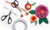 A flat lay of crafting supplies for making paper flowers, including scissors, tape, and pre-cut paper pieces. Anteprima dell’immagine prodotto