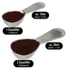 Two metal measuring spoons filled with coffee grounds are shown against a white background, with labels indicating their measurements. Produktbild-Vorschau