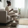 A woman sits on a couch holding a mug, with a side table next to her. Produktbild-Vorschau