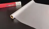 A roll of translucent window film is shown on a dark surface, with its packaging in the background. Podgląd zdjęcia produktu