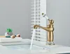 A close-up of a retro-style brass faucet with a ceramic handle, with water running into a sink. Makeup brushes and a small plant are visible on the side. Anteprima dell’immagine prodotto