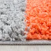 A close-up view of a shaggy carpet with a checkered pattern in gray and orange. Produktbild-Vorschau