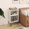 A white record player stand with vinyl records and decorative items is placed next to a brown leather sofa in a room. Náhľad obrázku produktu