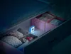 A small blue night light is placed inside an open drawer, illuminating baby clothes and accessories. Voir les images du produit