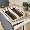 A close-up view of a toaster on a wooden countertop, with two small potted plants in the background. Podgląd zdjęcia produktu
