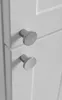 A close-up shot of two silver cabinet knobs on a white cabinet door. Podgląd zdjęcia produktu