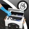 A hand in a blue glove is placing a scalpel into a mini high-temperature sterilizer. The sterilizer is open, revealing its interior. An overlay graphic with a hand and finger pointing is present in the top right corner. Voir les images du produit