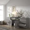 A modern living room with a gray sideboard featuring an electric fireplace, drawers, and cabinets. Decorated with artwork, a lamp, and a vase with branches. Produktbild-Vorschau