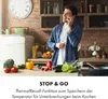 A man is talking on the phone in a kitchen while preparing food. Produktbild-Vorschau