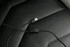 A close-up view of a black USB cable with an inline switch, lying on a black textured surface, likely a car seat or similar upholstery. Produktbild-Vorschau