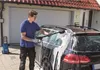 A man is washing a car with a pressure washer. Produktbild-Vorschau