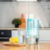 A water filter pitcher, a glass of water, and lemons are placed on a wooden table in a kitchen setting. Náhled obrázku produktu