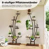 Two multi-tiered plant stands are displayed on a wooden deck, adorned with various potted plants and books. The background is a light-colored wall, suggesting an outdoor or semi-outdoor setting like a porch or patio. Podgląd zdjęcia produktu