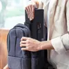 A person is placing a black projector into a gray backpack. Náhľad obrázku produktu