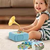 A young girl is playing with a toy gramophone and records on the floor. Náhľad obrázku produktu