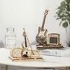 A wooden model of an electric guitar and amplifier, and a wooden model of a violin and case, are displayed on a table. Voir les images du produit
