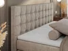 A close-up view of a tufted beige headboard and a white mattress on a bed. Produktbild-Vorschau
