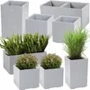 A collection of modern, light gray concrete planters of various sizes and shapes, some containing plants. Anteprima dell’immagine prodotto