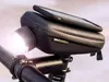 A close-up shot of a black SP Connect Wedge Case Set attached to a bicycle handlebar, with a smartphone resting on top and a bright LED light illuminating the foreground. Anteprima dell’immagine prodotto