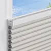 A close-up view of a beige honeycomb blind installed on a window, with a view of the sky and trees outside. Produktbild-Vorschau
