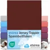 A product image showing a burgundy fitted sheet, with other colored sheets stacked behind it, and cotton bolls in the foreground. Produktbild-Vorschau