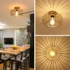 A collage of images showcasing a gold metal ceiling light fixture with a cage design, casting sunburst-like shadows on the ceiling. One image shows the light in a room setting above a dining table, while the other two are close-ups of the fixture itself. Náhled obrázku produktu
