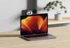 A laptop and a phone mounted on the wall behind it. Produktbild-Vorschau