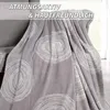 A gray blanket with a white circular pattern is draped over a chair, with text overlays at the top. Produktbild-Vorschau