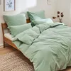 A neatly made bed with green bedding in a bedroom setting. Produktbild-Vorschau