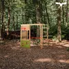 A wooden climbing frame with a basketball hoop and a green panel is set up in a forest clearing. Podgląd zdjęcia produktu