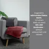 A burgundy fleece blanket is draped over a gray armchair, next to a large green leaf plant. Náhľad obrázku produktu