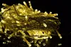 A tangled pile of warm white LED string lights on a black reflective surface. Produktbild-Vorschau