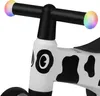 Close-up of the handlebars and front of a children's balance bike with a cow print design. Náhled obrázku produktu