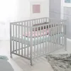 A baby crib with bedding in a room setting. Produktbild-Vorschau