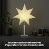 A decorative paper star lamp is displayed on a dark cabinet, with a potted plant on the left and gift boxes on the right. The text "Wunderschöner dekorativer Papierstern für den Innenbereich" is overlaid at the bottom. Podgląd zdjęcia produktu