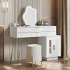 A white vanity table with a unique mirror and stool, set against a textured wall. Voir les images du produit
