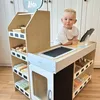 A young child is playing at a wooden market stand. Produktbild-Vorschau
