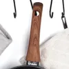 A close-up view of a pan handle hanging on a hook, with fabric items on either side. Produktbild-Vorschau