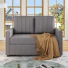 A gray sofa bed with a brown throw blanket is shown in a living room setting with large windows in the background.