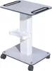 A white rolling trolley with a flat top surface, a small shelf, and a square base with wheels. Náhled obrázku produktu