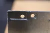 A close-up view of a metal object with two holes punched through it. Anteprima dell’immagine prodotto