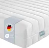 A close-up, angled view of a white mattress with a blue label and a grey band with German flag and certifications. Produktbild-Vorschau